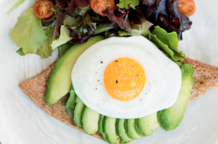 Tostada de pan rústico con aguacate, huevo frito y ensalada