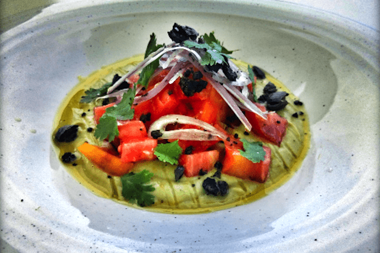 Ensalada de tomate sobre crema de aguacate, pepino, lima y cilantro