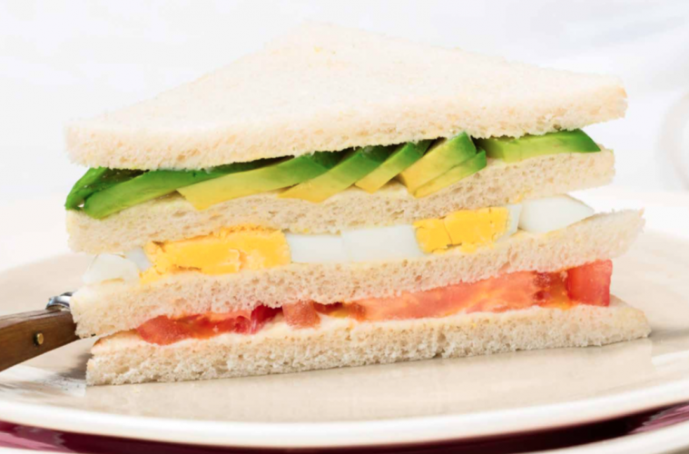 Sándwich de aguacate, huevo duro, mayonesa y tomate que empieza a madurar
