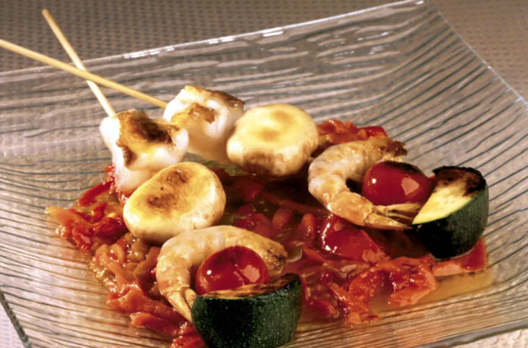 Brochetas de rape y langostinos sobre pimientos asados