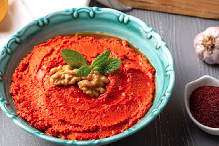 Bol de muhammara con pimientos rojos que empiecen a madurar
